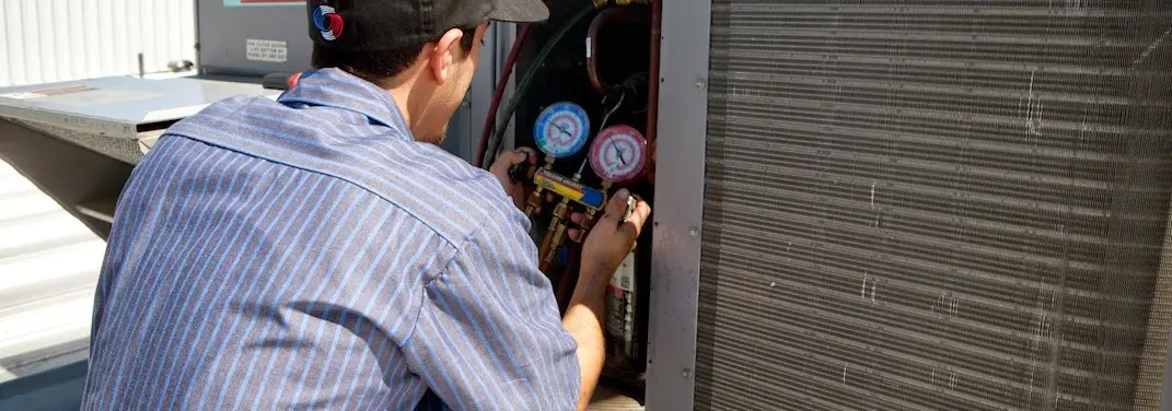HVAC technician servicing a condenser unit in Parkville